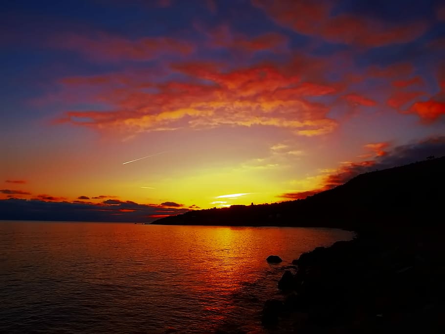 silhouette photo of island during golden hour, silhouette photo of mountains near open sea under cloudy sky during golden hour HD wallpaper