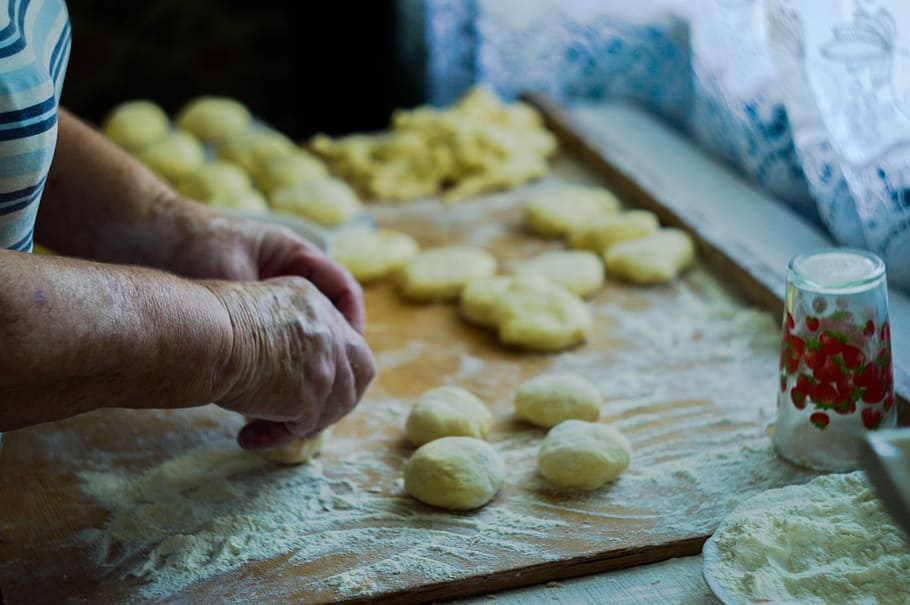 person making dough on brown wooden board, person molding dough on wooden table HD wallpaper