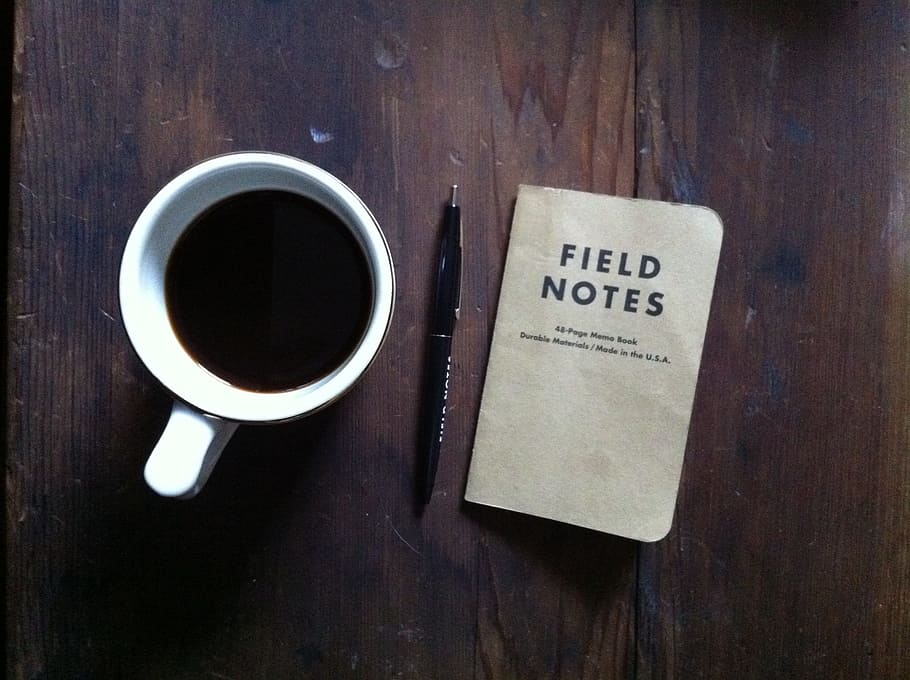 close-up photography of coffee inside white mug beside black click pen and field notes book HD wallpaper