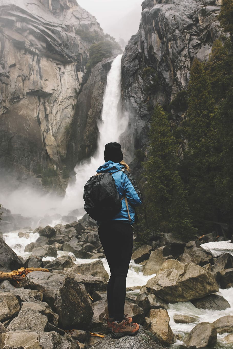 woman standing on rock facing waterfalls, photo of man facing waterfalls during daytime HD wallpaper