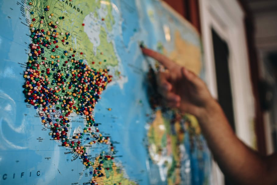 person pointing at a certain location in a map, pins, travel