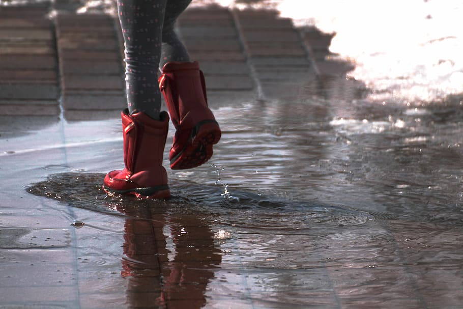 woman wears red rain boots, splash, puddle, fun, rubber, wet