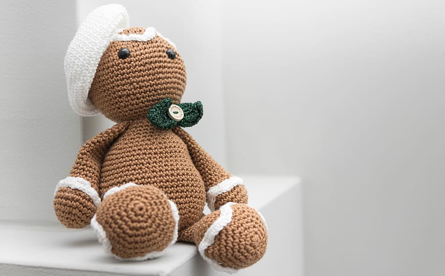 brown and white amigurumi doll, brown bear amigurumi doll on white wooden table