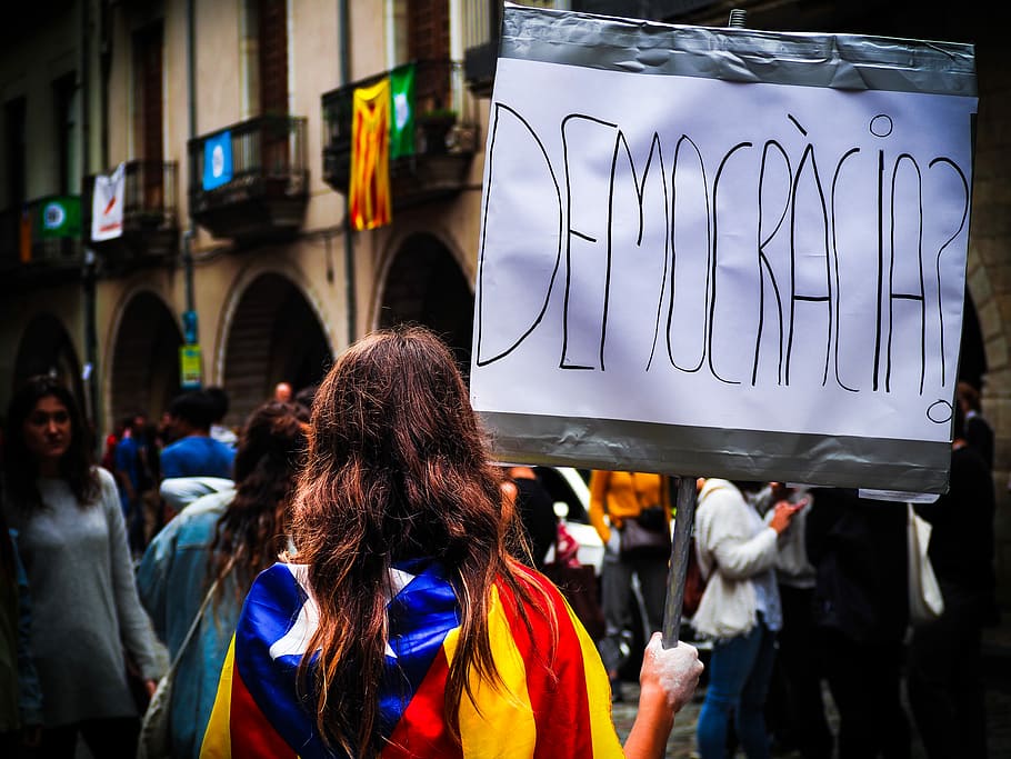 woman holding democracia signage, person wearing multicolored clothes while holding gray signboard HD wallpaper
