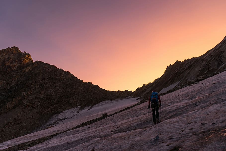 person walking uphill during golden hour, person walking on snow covered mountain HD wallpaper