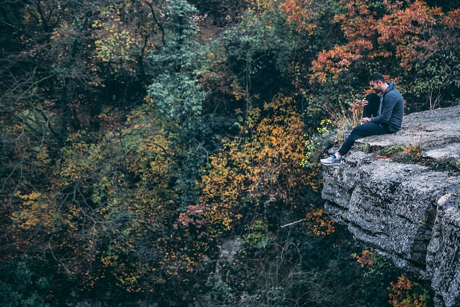 Man In Hoodie Sitting On Rock Cliff, adventure, alone, daylight HD wallpaper