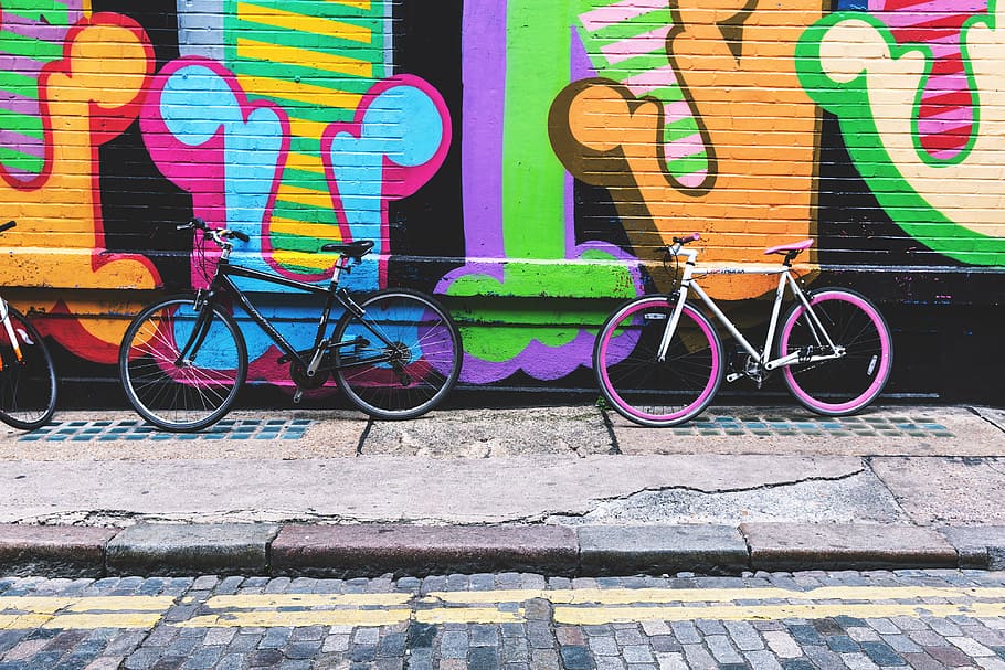 Bicycles stand against a street-art covered wall in the city, HD wallpaper