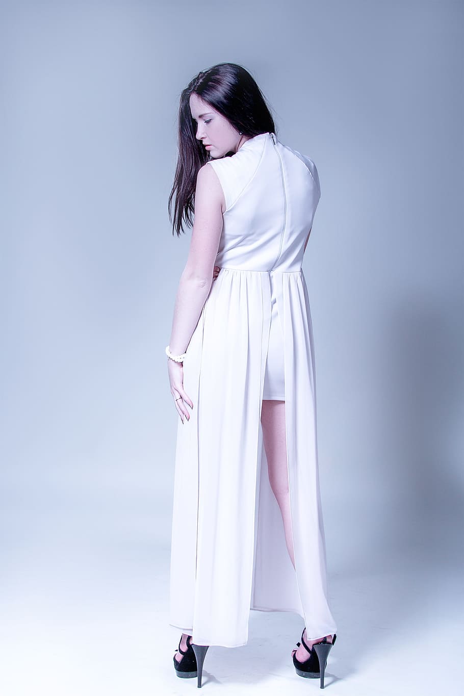 woman wearing white sleeveless long dress with slit and black heeled sandals