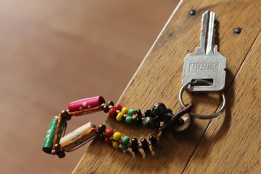 gray Sentry key with multicolored keychain on brown wooden surface, HD wallpaper
