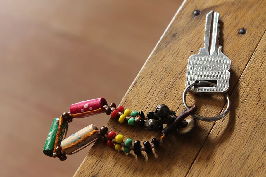 gray Sentry key with multicolored keychain on brown wooden surface HD wallpaper