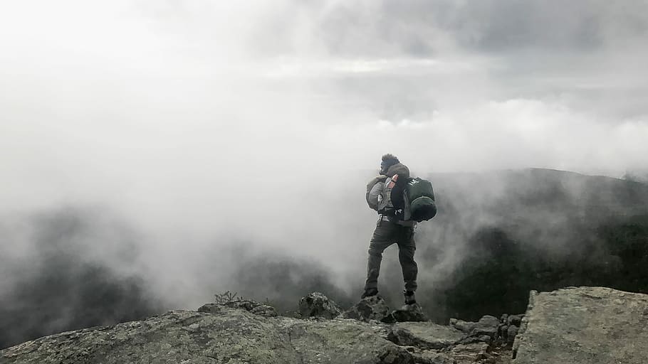 person carrying black hiking bag, person standing on mountain peak in front of fogs HD wallpaper