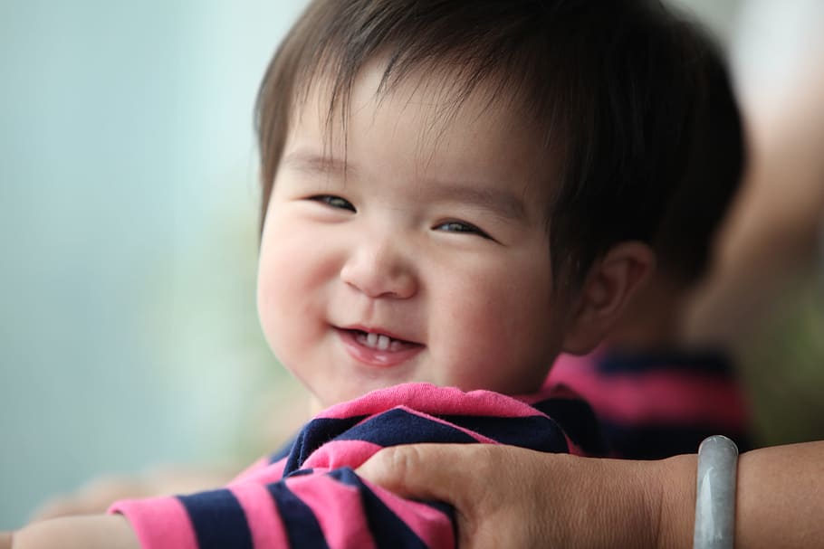 macro shot of smiling baby boy wearing black and blue stripe shirt