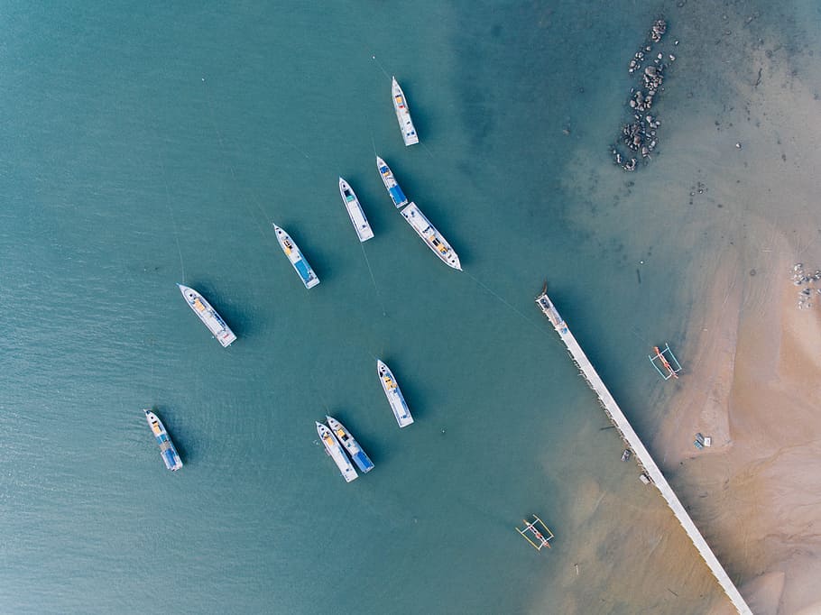 white and blue boat near white dock at daytime, aerial photography of 10 yacht sailing on green ocean near seashore HD wallpaper