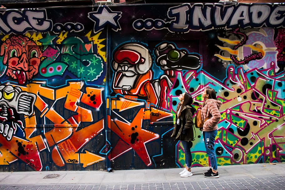 two women staring at graffiti on wall, people, street, art, paint