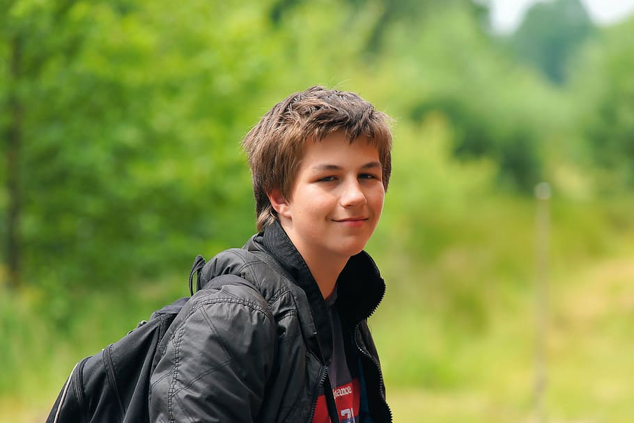 boy wearing black jacket and backpack standing near plant, human HD wallpaper
