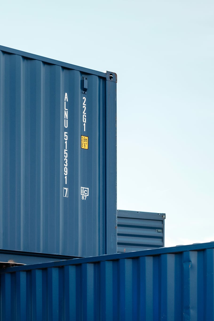 black cargo tanks piled up, gray intermodal containers stacking together under clear blue sky