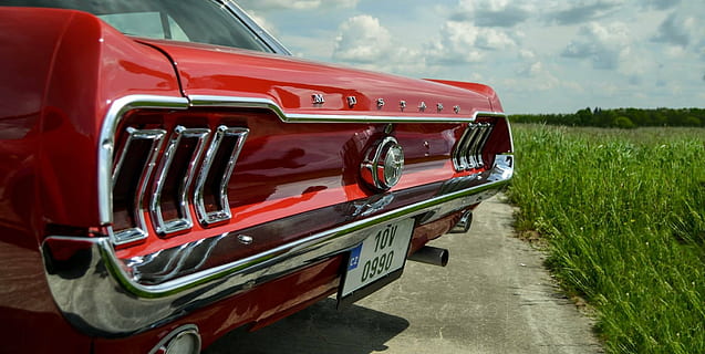 red Ford Mustang coupe parked on paved road near grass field at daytime HD wallpaper