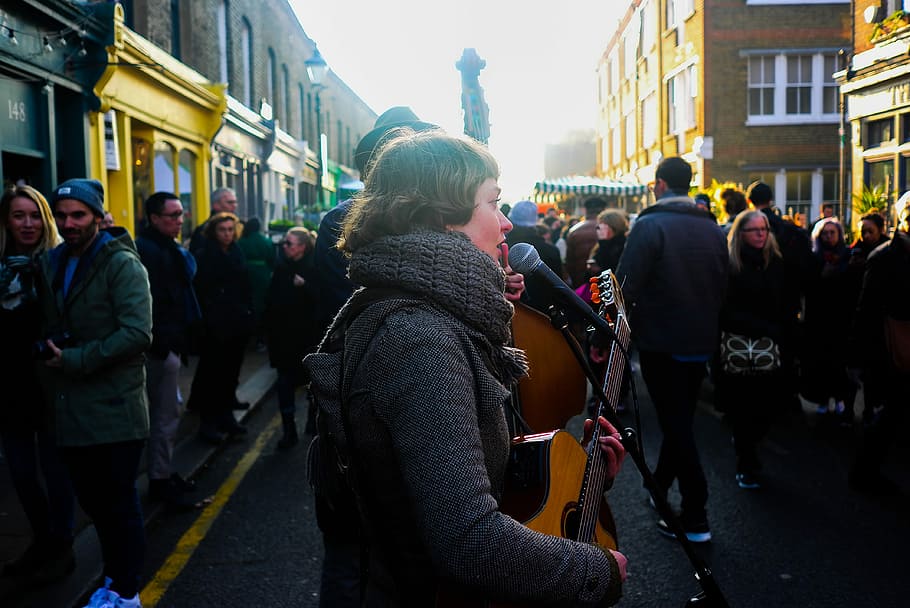 woman holding acoustic guitar while singing, two street performers HD wallpaper