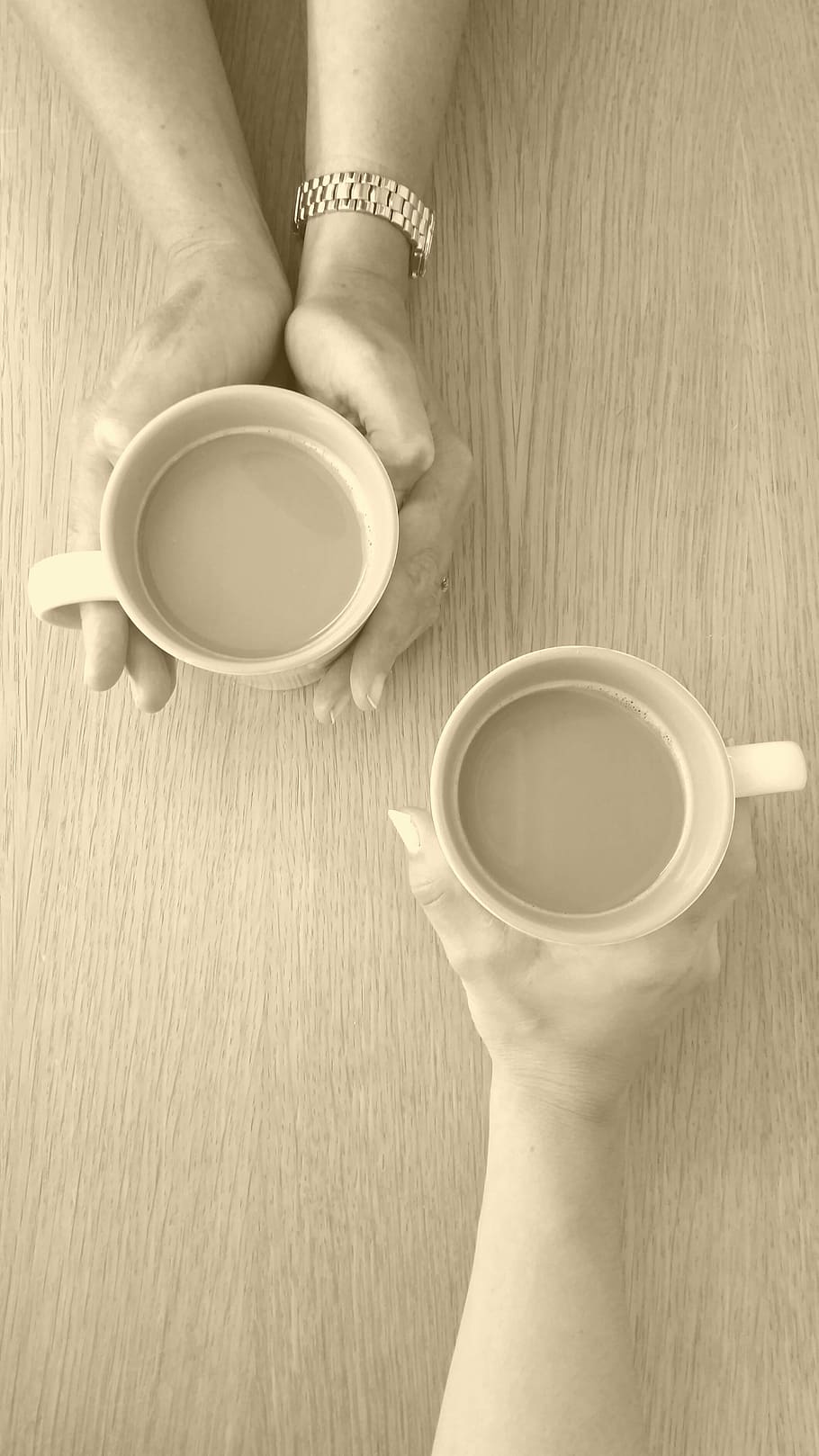 photographed of two person holding mugs, coffee, chat, conversation