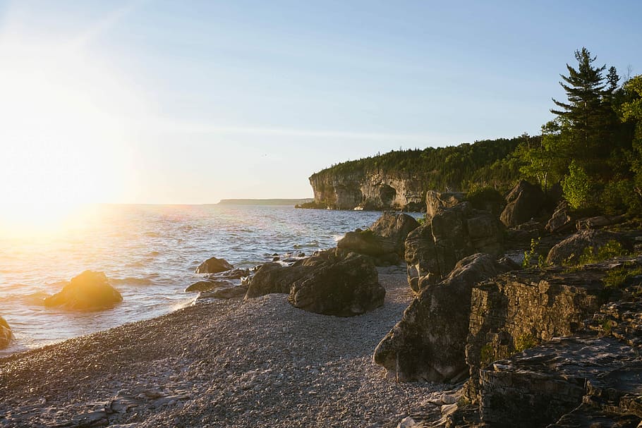 landscape photography of white sand rocky beach, rocky island beside sea shore HD wallpaper