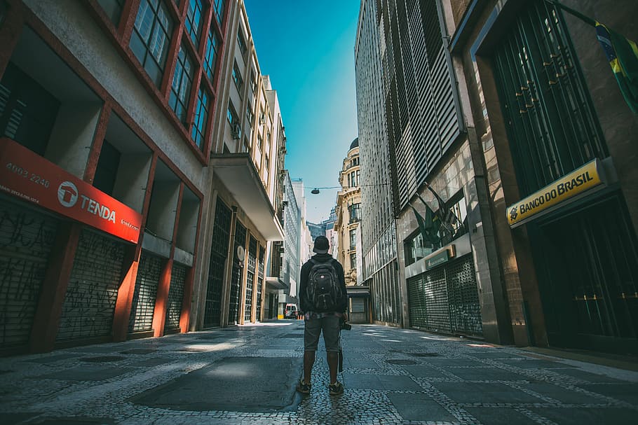 man standing in the middle of street surrounded with buildings