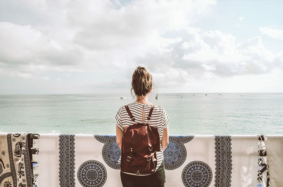 woman standing in front of body of water during daytime, woman in black and white striped shirt standing in front of sea HD wallpaper