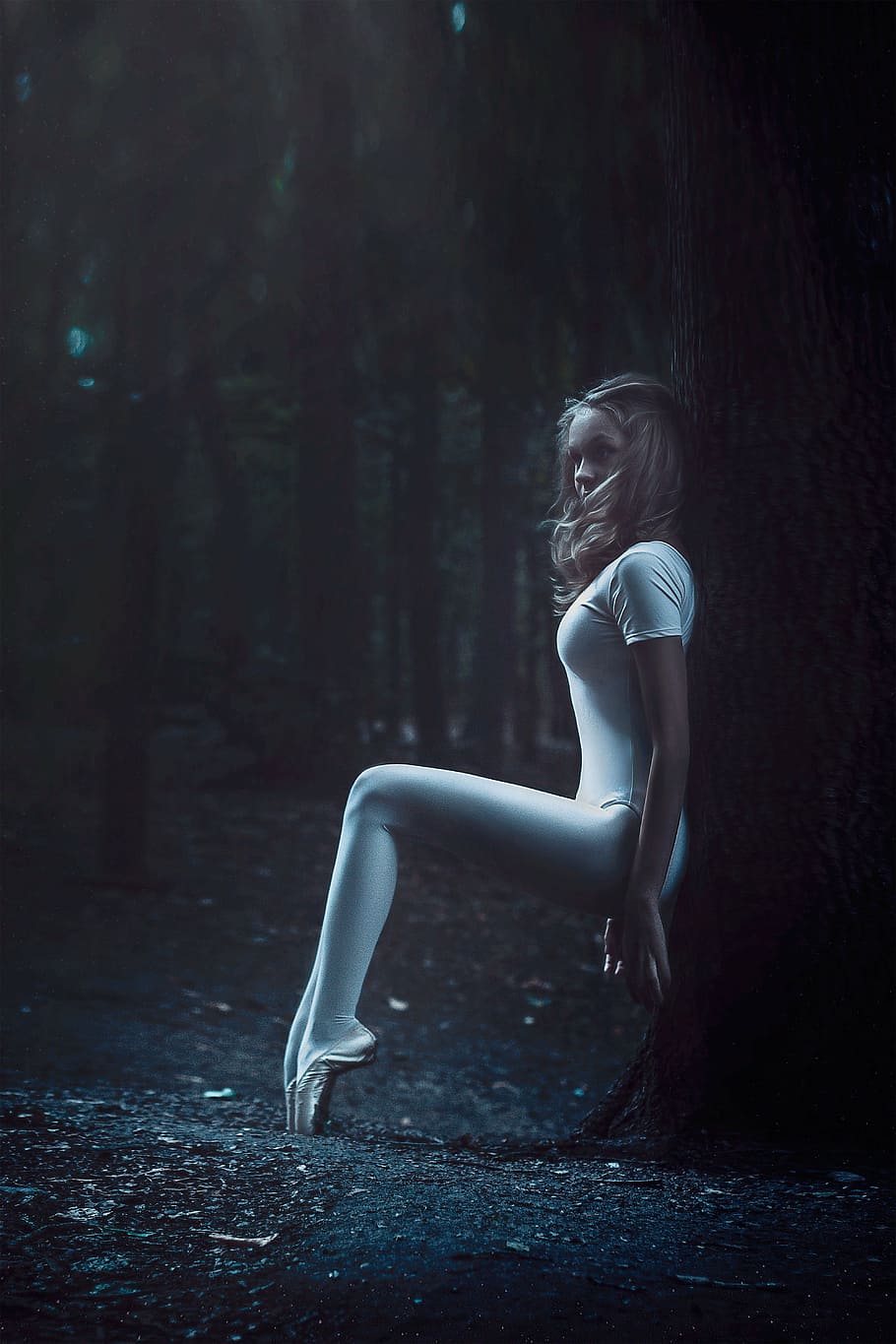 woman in white leggings sitting beside the tree, ballerina in the forest