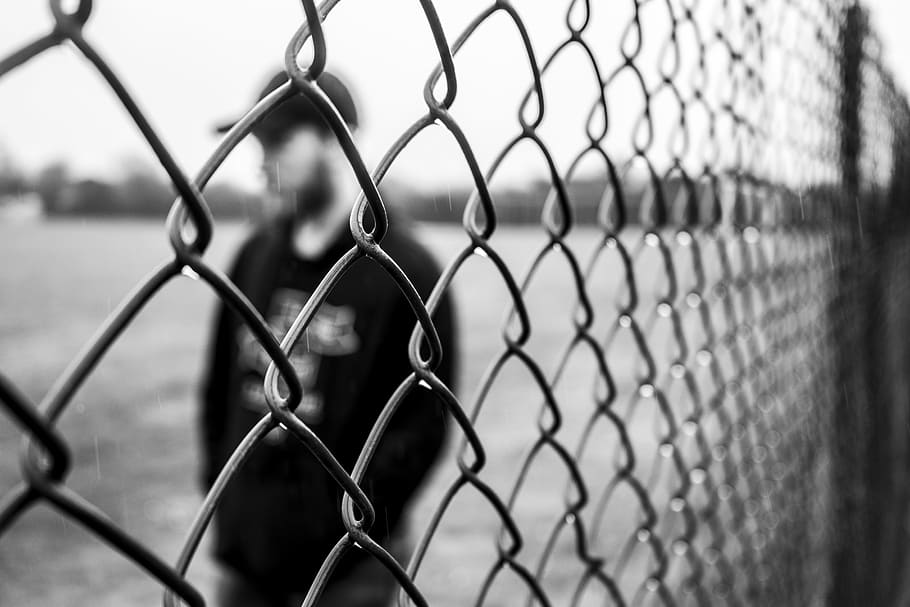 man in long-sleeved shirt standing near chain link fence, man standing beside gray stainless steel wire fence, HD wallpaper