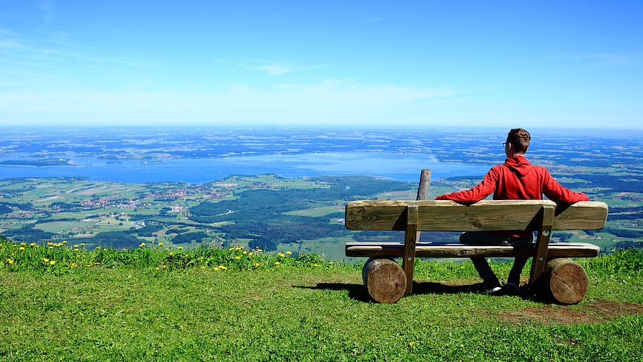 man in red pullover hoodie sitting on brown wooden bench over-viewing planes HD wallpaper
