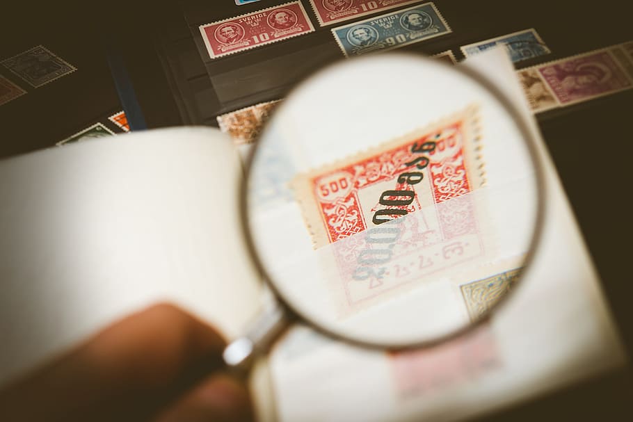 person holding magnifying glass, philatelist, stamp collection