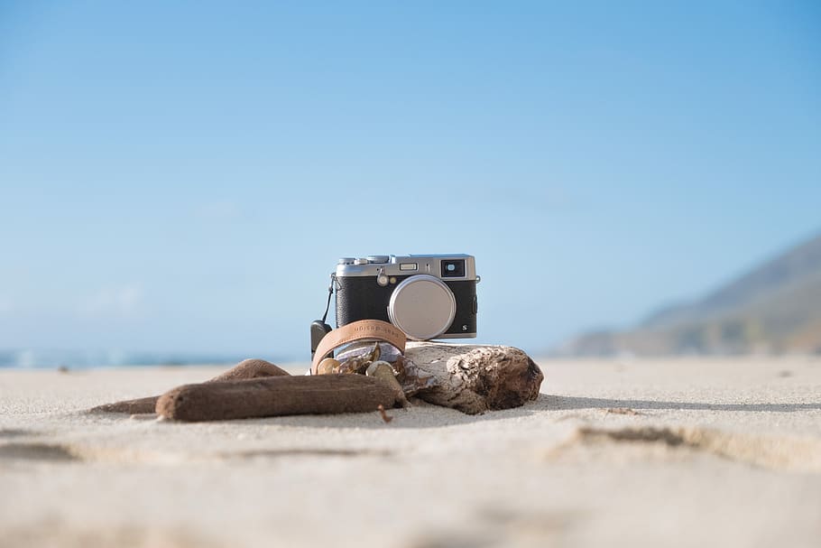 selective focus photography of camera on sand, gray and black DSLR camera on driftwood HD wallpaper