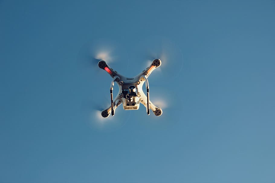 low angle photography of RC quadcopter at mid air, white drone taking flight in sky during daytime HD wallpaper