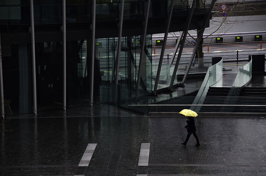 person walking on the street holding his yellow umbrella while raining