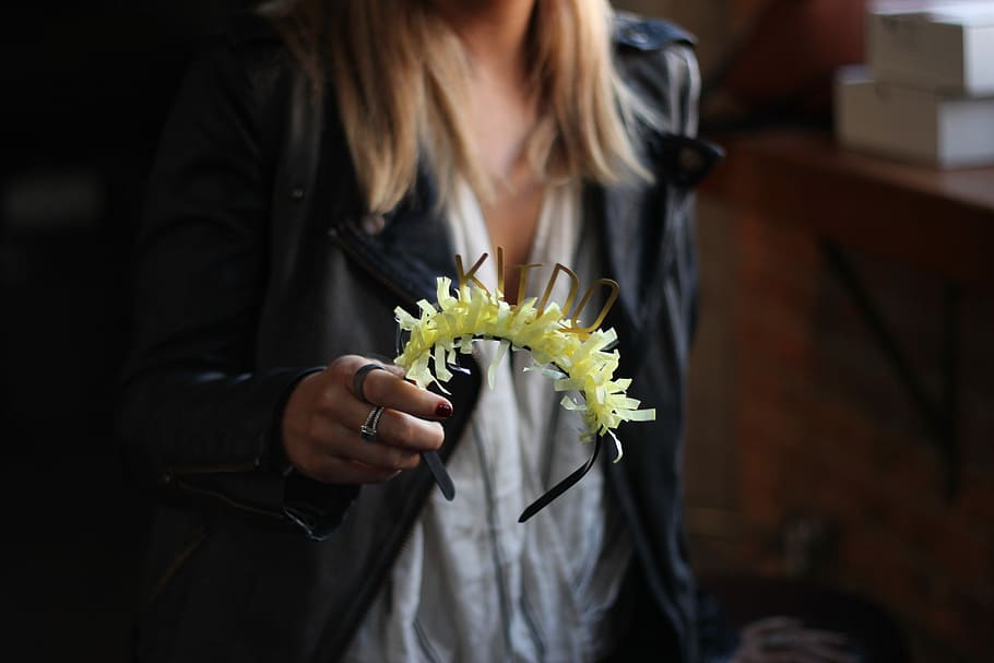 person holding green and black headband, woman holding headband with yellow flower accent HD wallpaper