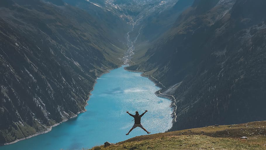 person jumping, man jumping on top of mountain in a distance of a river HD wallpaper
