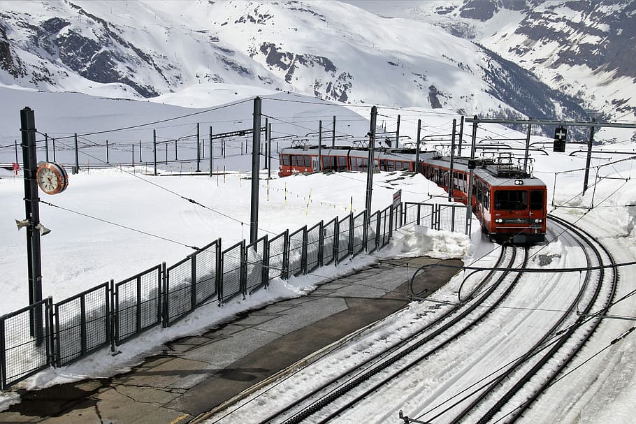 red train on railway during winter at daytime, pull station, zermatt