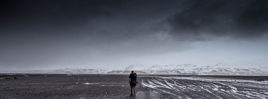 Man Standing on Gray Dessert Under Gray Cloudy Sky during Daytime HD wallpaper