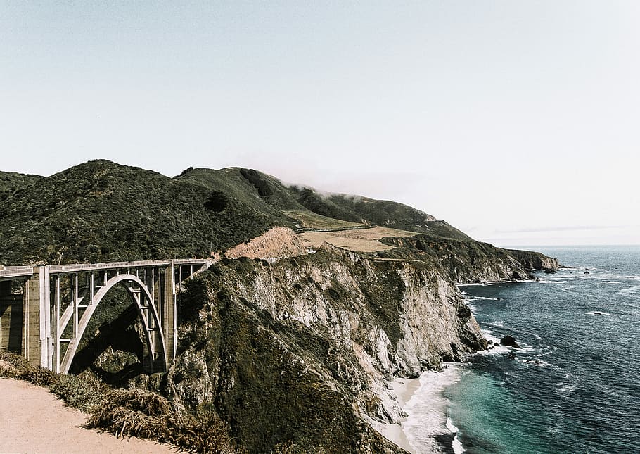 photo of white bridge on mountain, gray concrete bridge next to mountains and sea HD wallpaper
