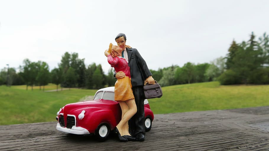 couple ceramic figurine on brown surface, kissing, car, man, woman