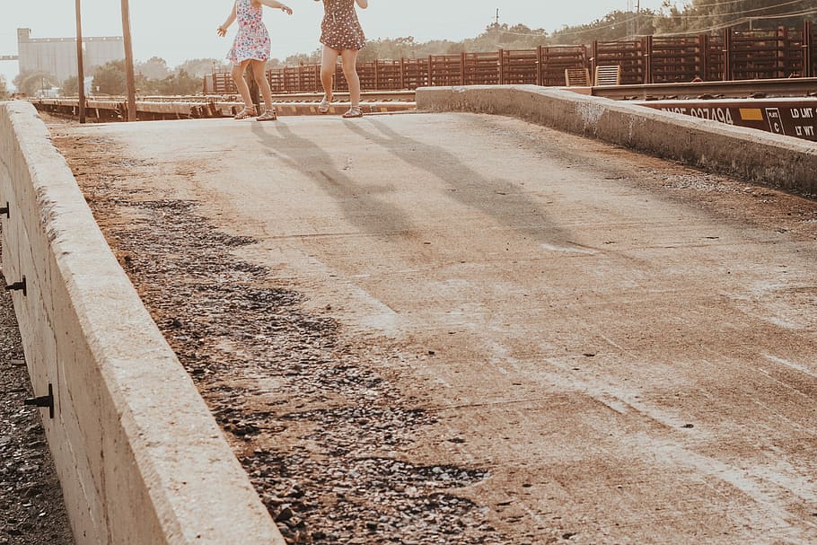 two person walking on ground, two women standing on gray concrete road during daytime HD wallpaper