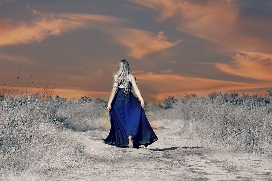woman in navy-blue cage-back floor-length dress walking through the rocky road surrounded with grass during golden hour, HD wallpaper