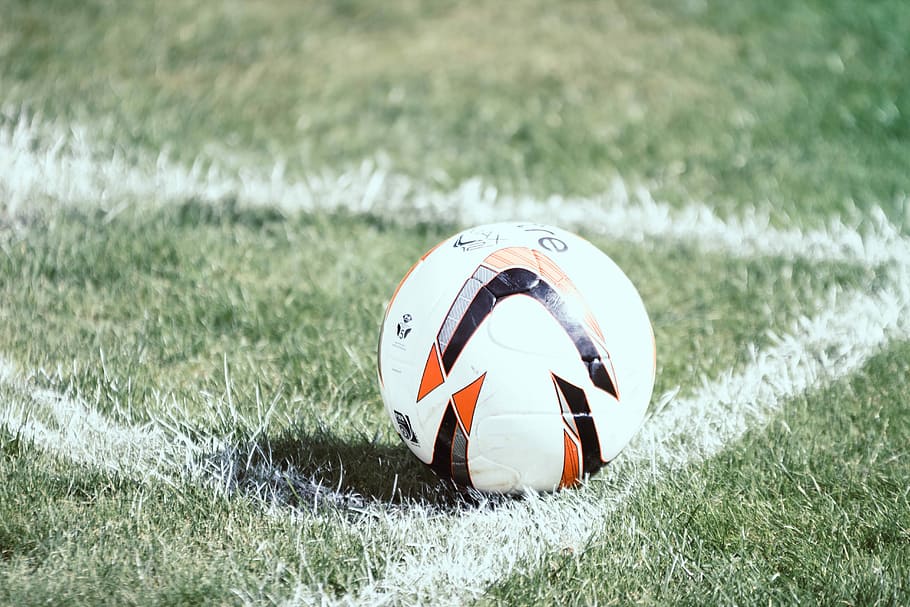 white, orange, and black soccer ball on field, white and black soccer ball on green grass field