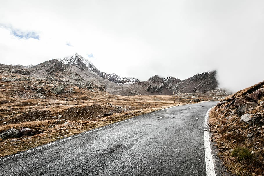 photo of road across mountain during daytime, gray road near mountain range HD wallpaper