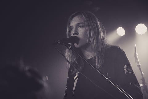 man performing on stage, grayscale photo of vocalist, long haired HD wallpaper