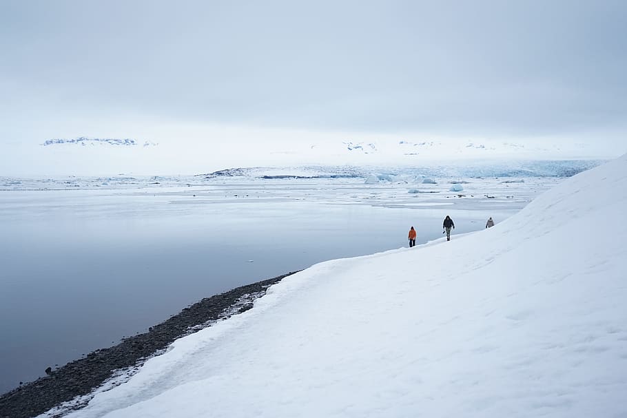 two people walking on snow covered ground, mountain covered with snow HD wallpaper