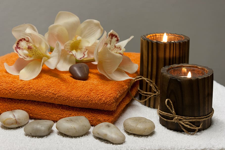 white orchids and two brown candles on top of orange towel closeup photography, HD wallpaper