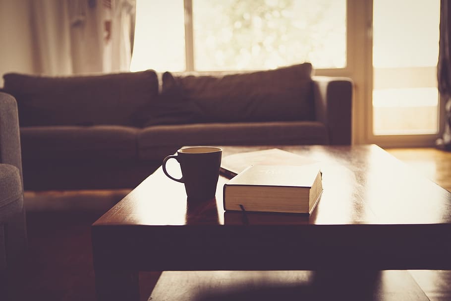 black ceramic mug on brown wooden coffee table, living room, couch