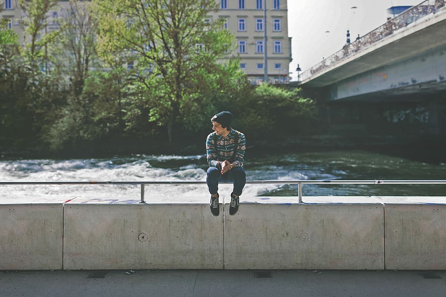 man in green and brown dress shirt sitting on grey metal hand rail near river, HD wallpaper