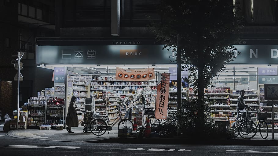 photo of man and woman standing near bicycles and opened establishment, bicycles parked outside of store at nighttime HD wallpaper