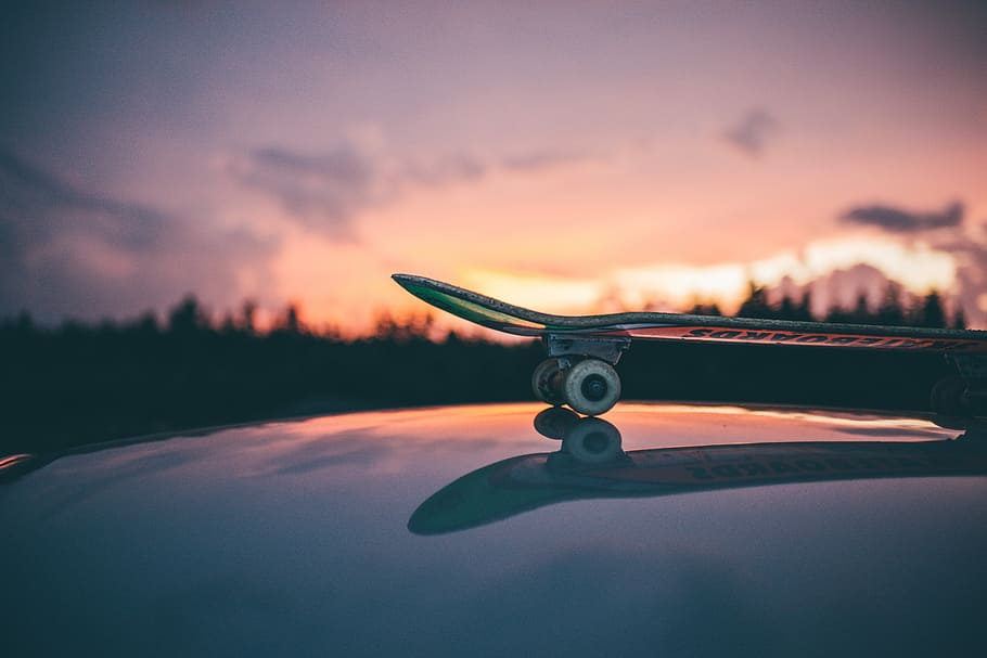 skateboard on top of glazed surface, silhouette photography of skateboard near high trees and mountain HD wallpaper